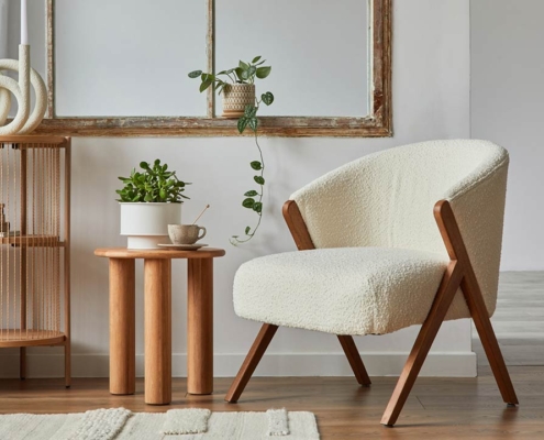 Stylish compositon of modern living room interior with frotte armchair, wooden commode, side table and elegant home accessories