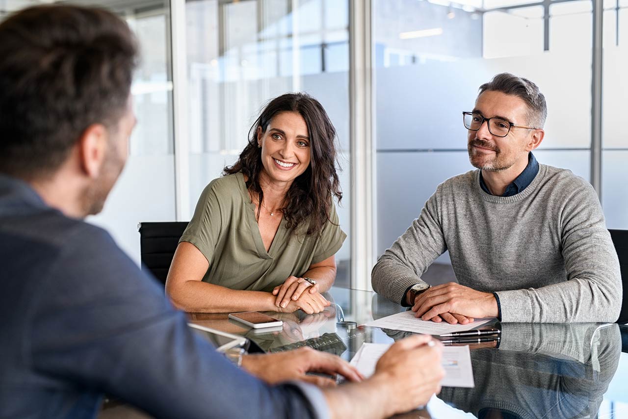 Happy middle aged couple meeting loan advisor to buy a new home