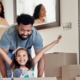 A young father having fun with his daughter while pushing her in a moving box