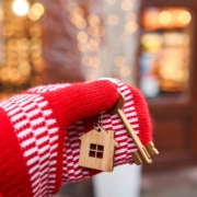 Hand in red mitten holding key with house shaped keychain