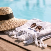 Sunglasses and straw hat on the wooden floor at the pool