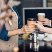 Barista served take away hot coffee cup to customer at counter bar in cafe restaurant