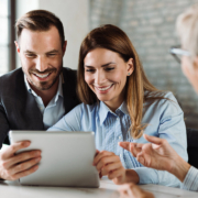 Happy couple using tablet while having a meeting with their real estate agent in the office